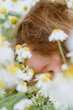 A person's face is surrounded by daisies.