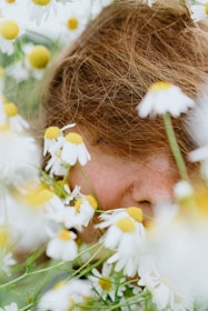 A person's face is surrounded by daisies.