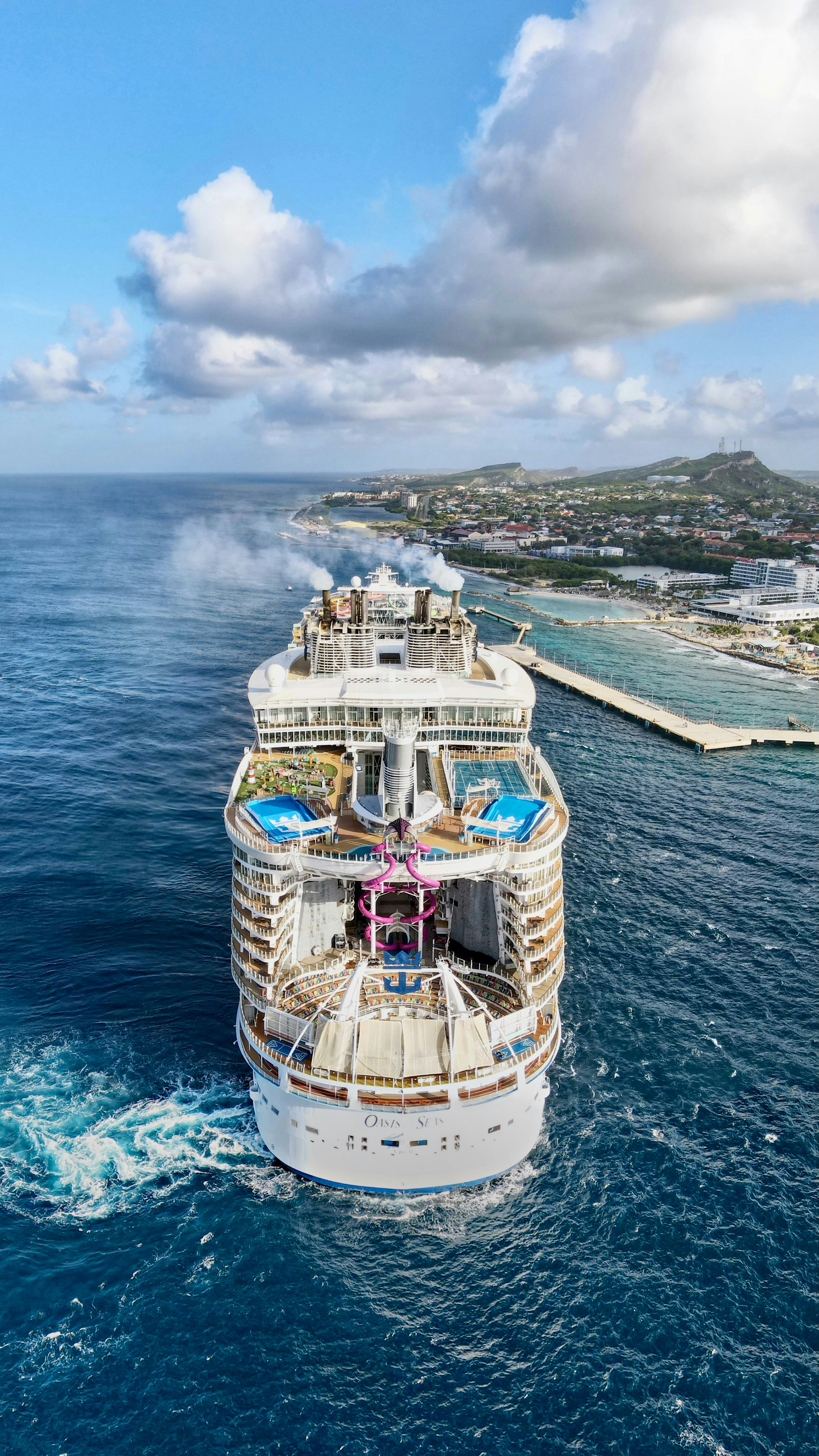 A cruise ship sails near a coastal town.