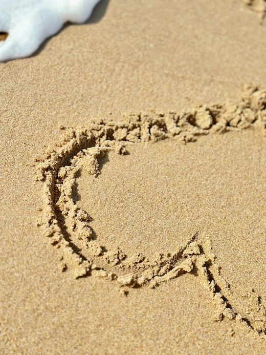 A heart is drawn in sand.