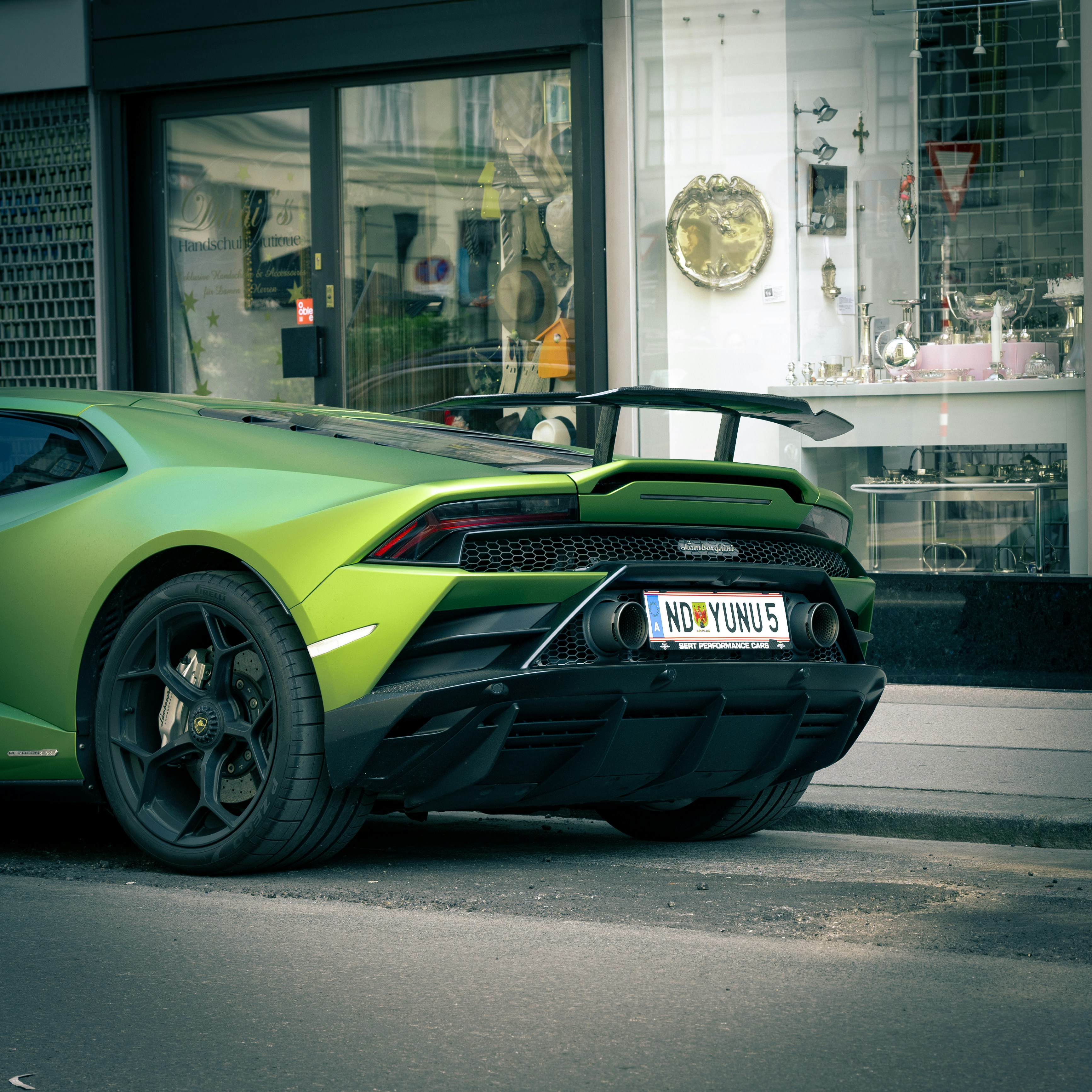Green lamborghini is parked near a shop.