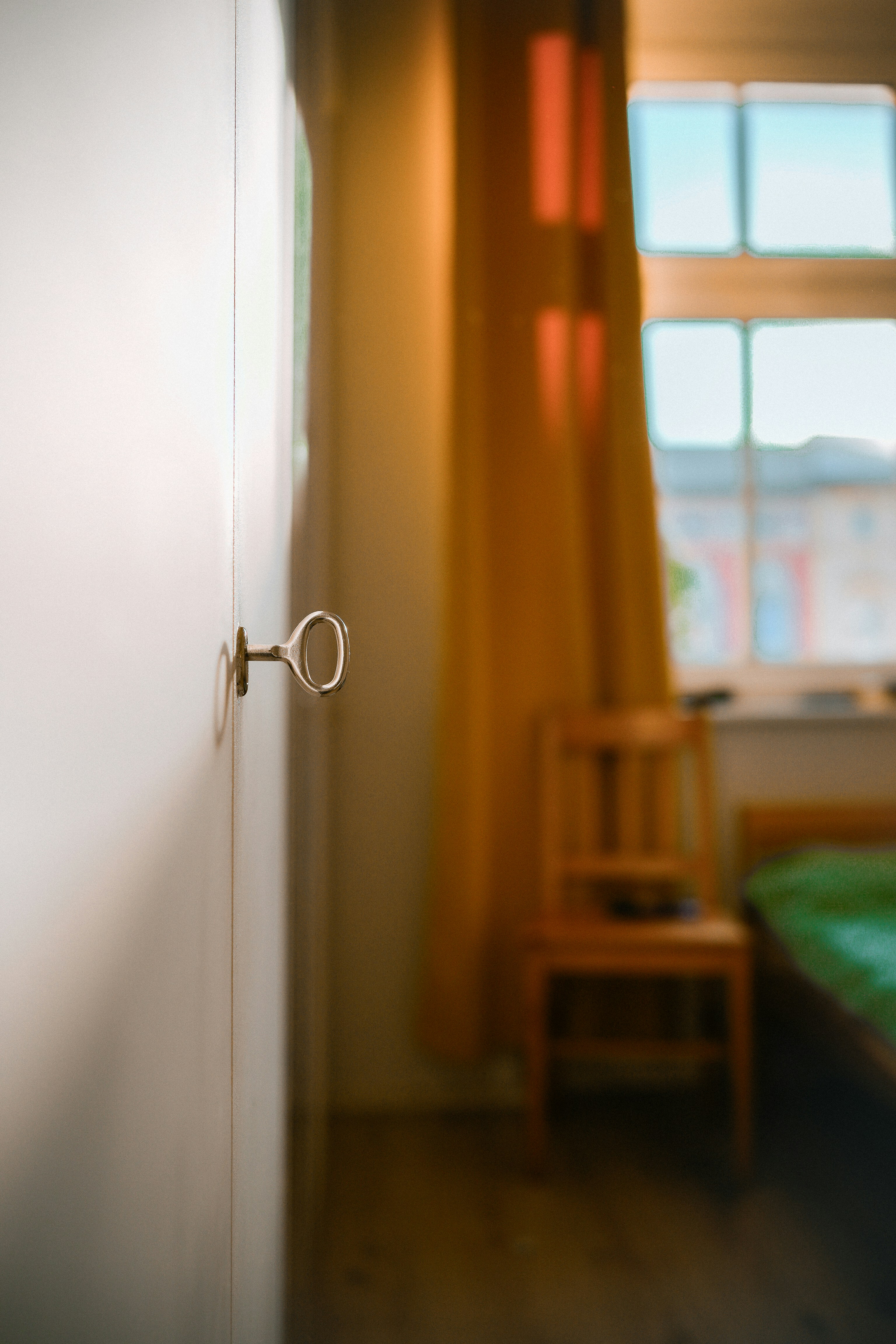 A key is in a white door, with a room in view.