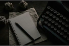 A typewriter, notepad, and crumpled paper are shown.