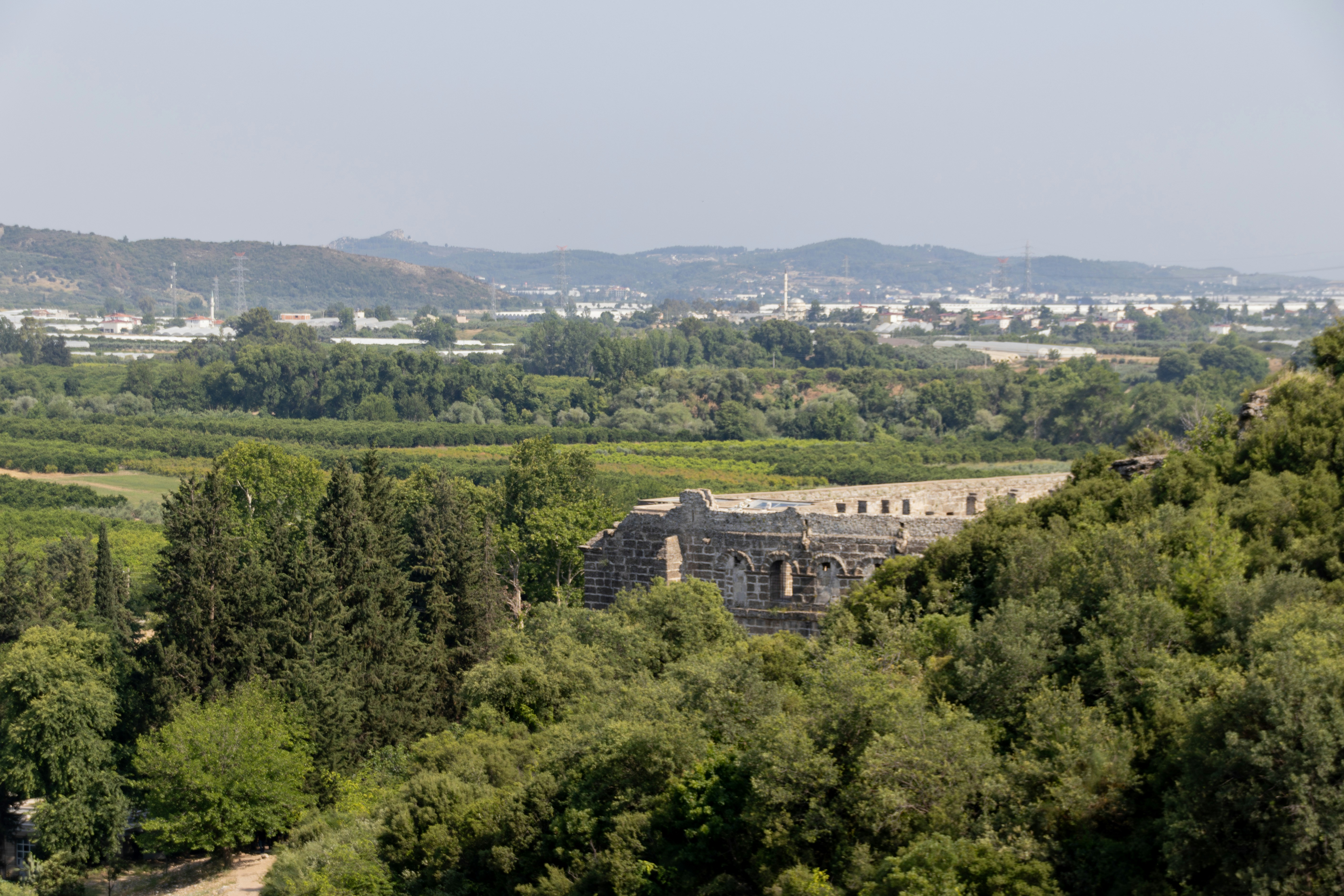 An ancient roman ruin stands amidst lush greenery.