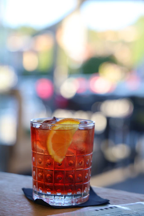 Burgundy Negroni garnished with an orange slice, evening light