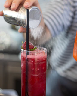 A bartender is sprinkling something on the drink.