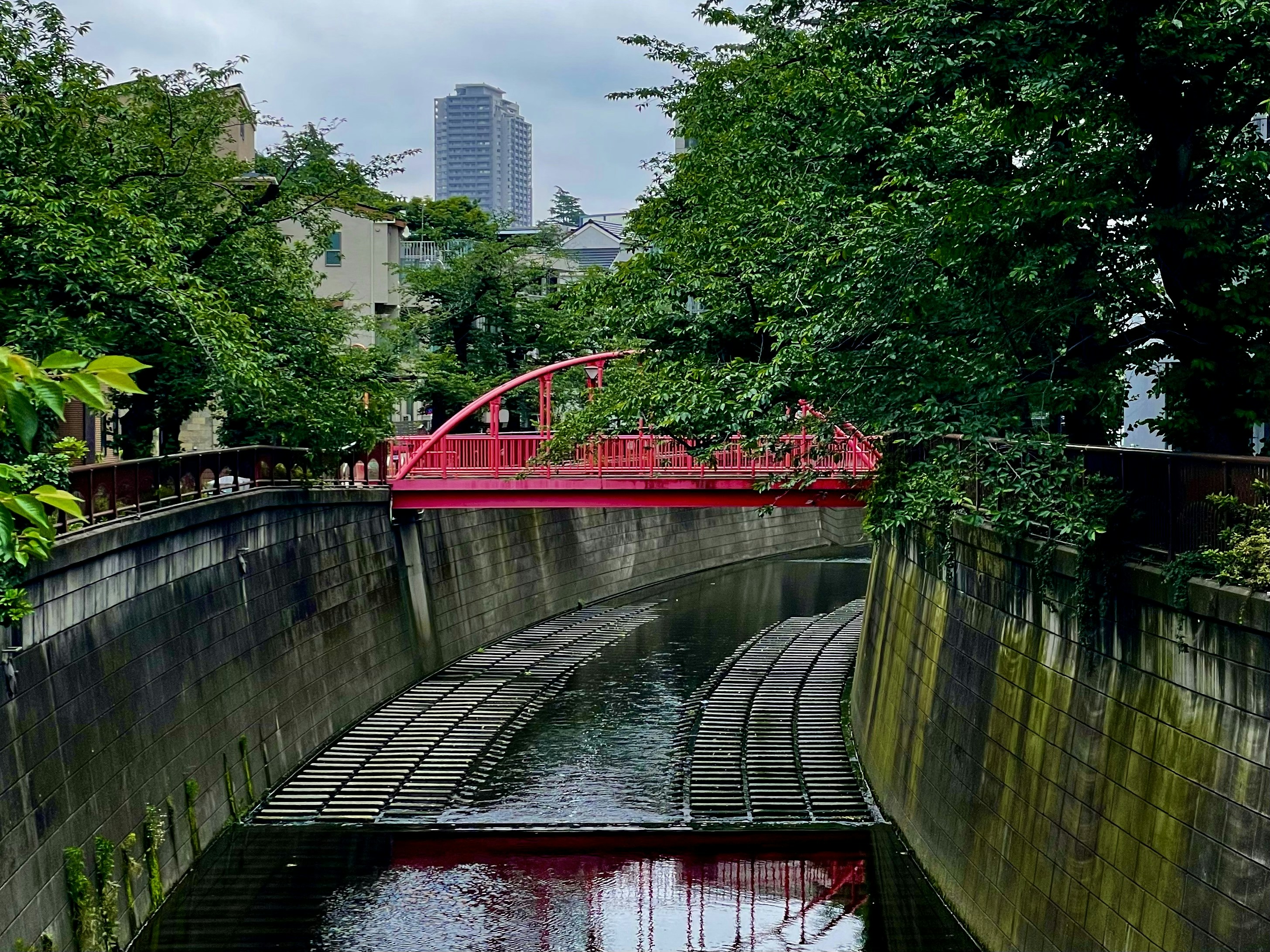 Eine rote Brücke wölbt sich über einen Wasserweg.