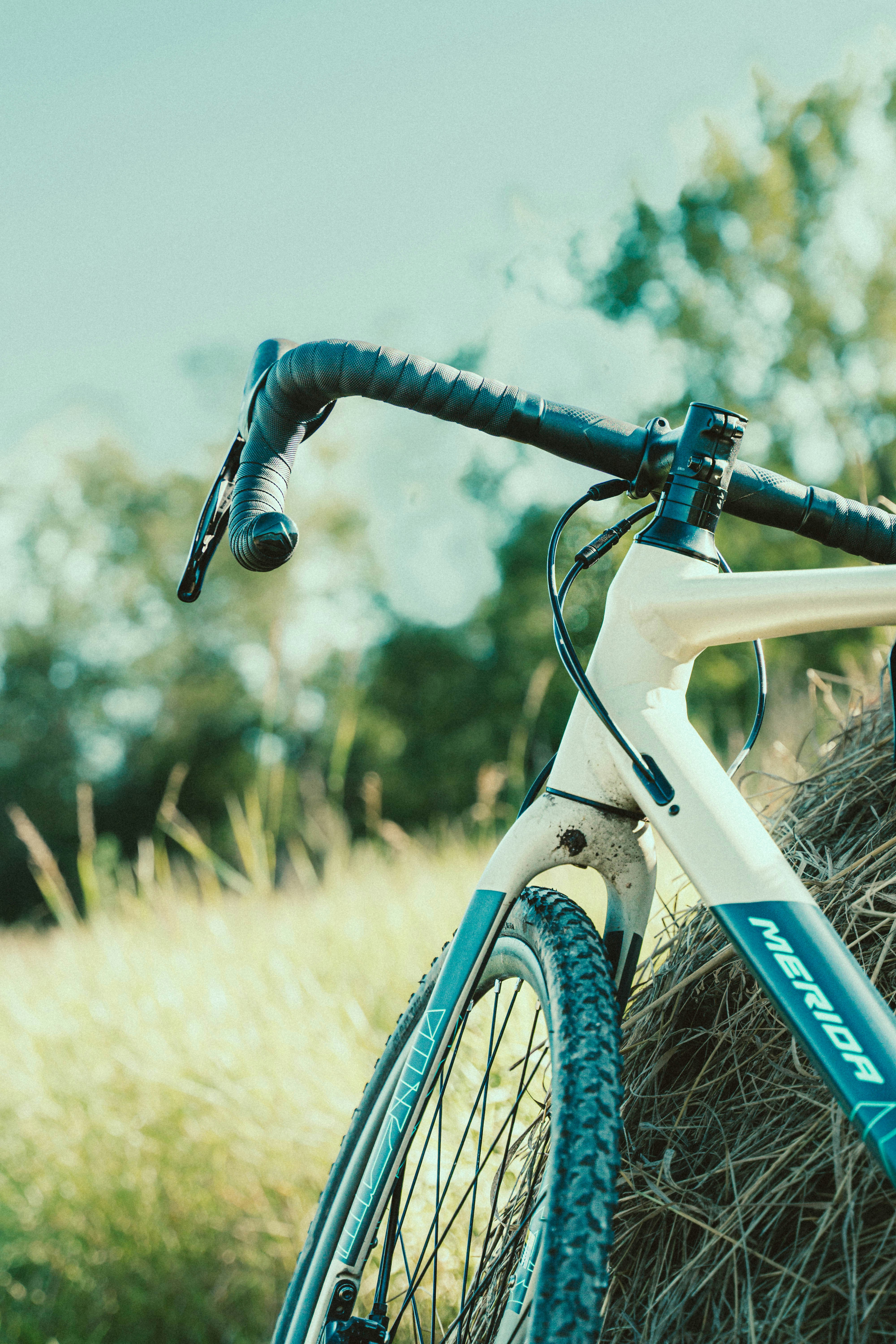A bicycle rests against hay in the sunshine.