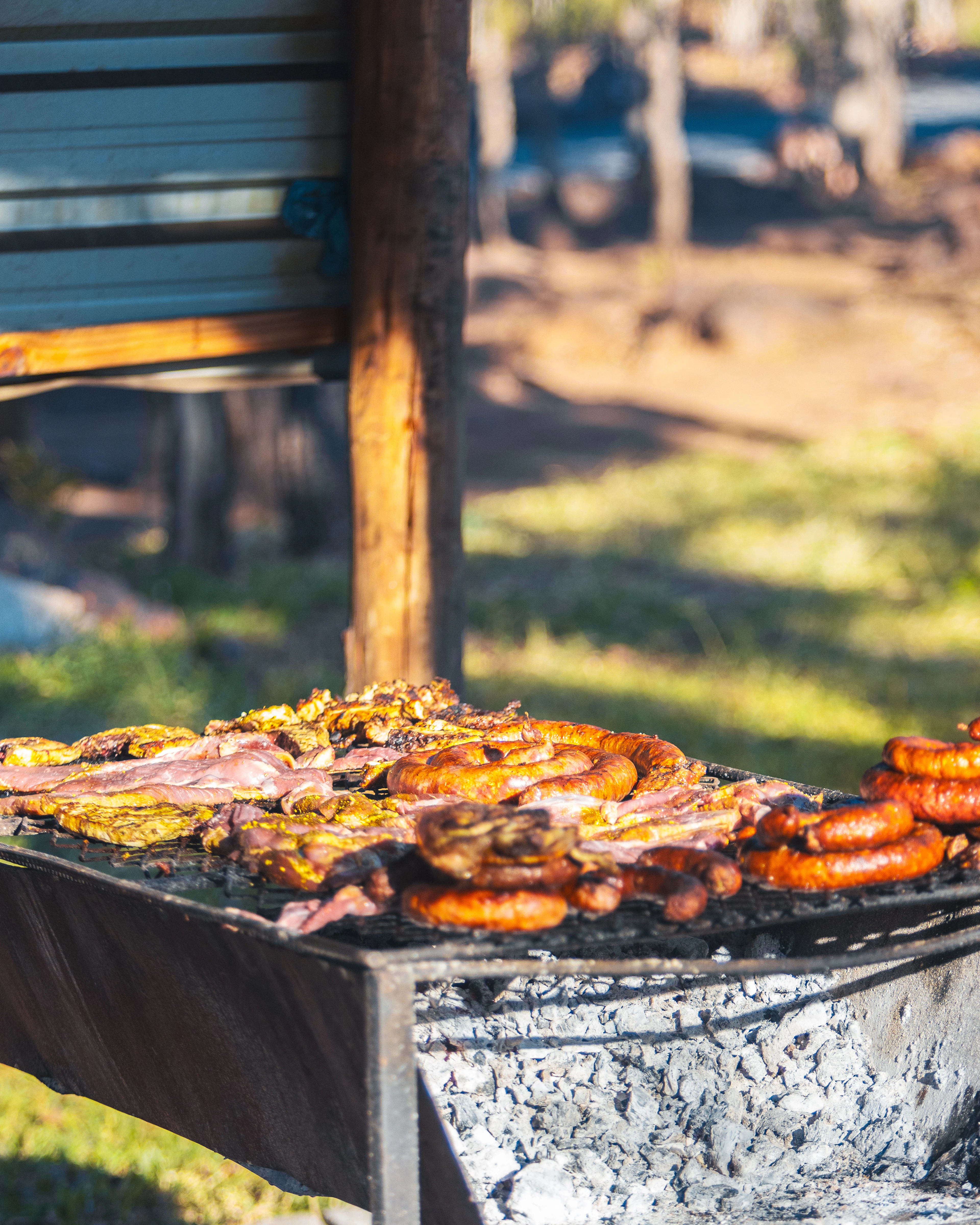 Coils of sausage, bacon and cuts of meat grilling over charcoal on an outdoor braai in Africa