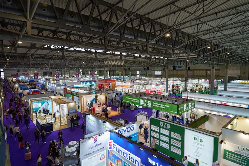 A busy indoor trade exhibition hall full of vendor booths