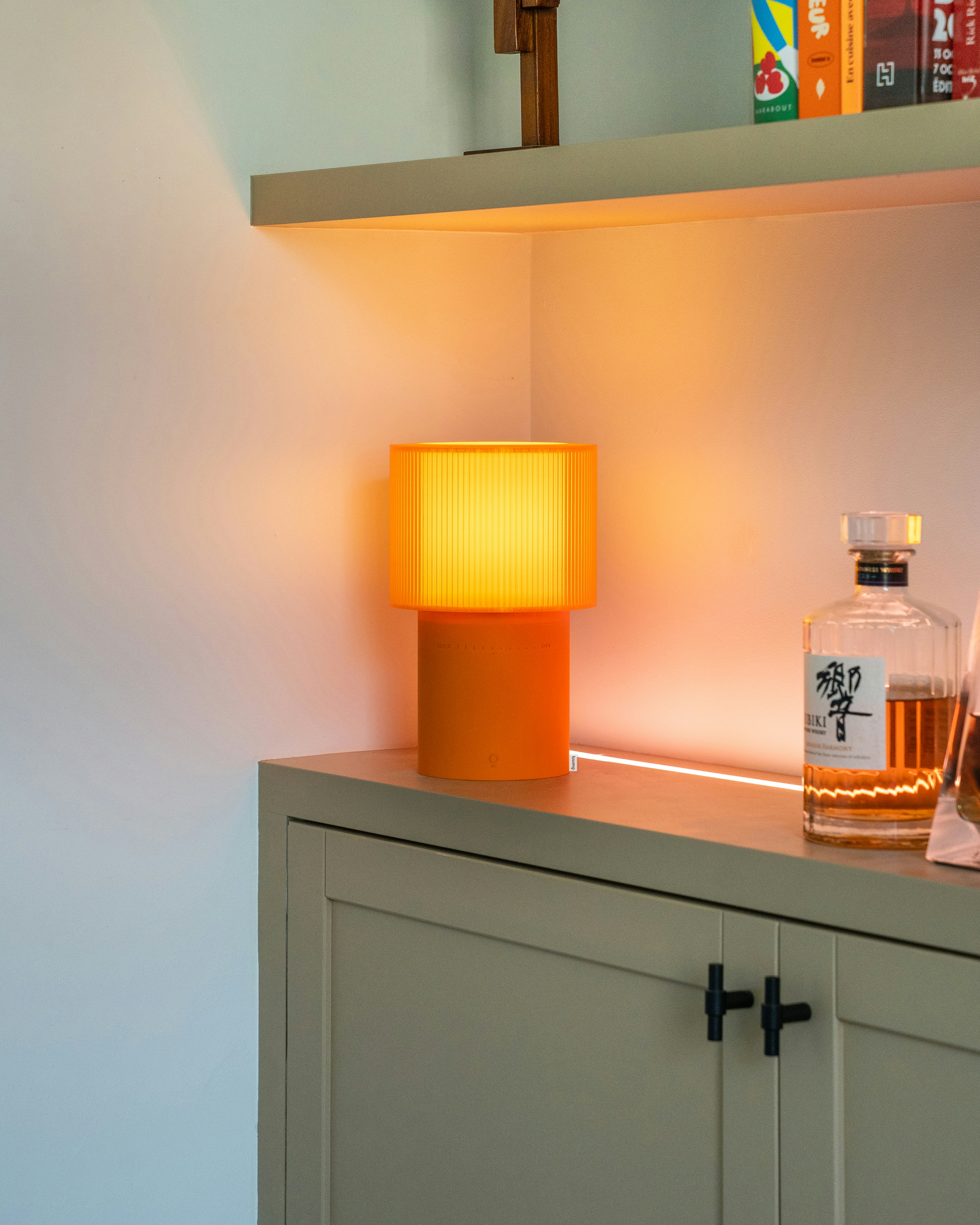 Warm orange lamp lights up a cabinet.