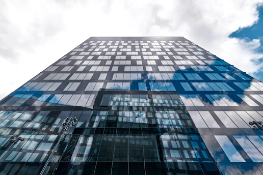 A tall building reflects the sky's clouds