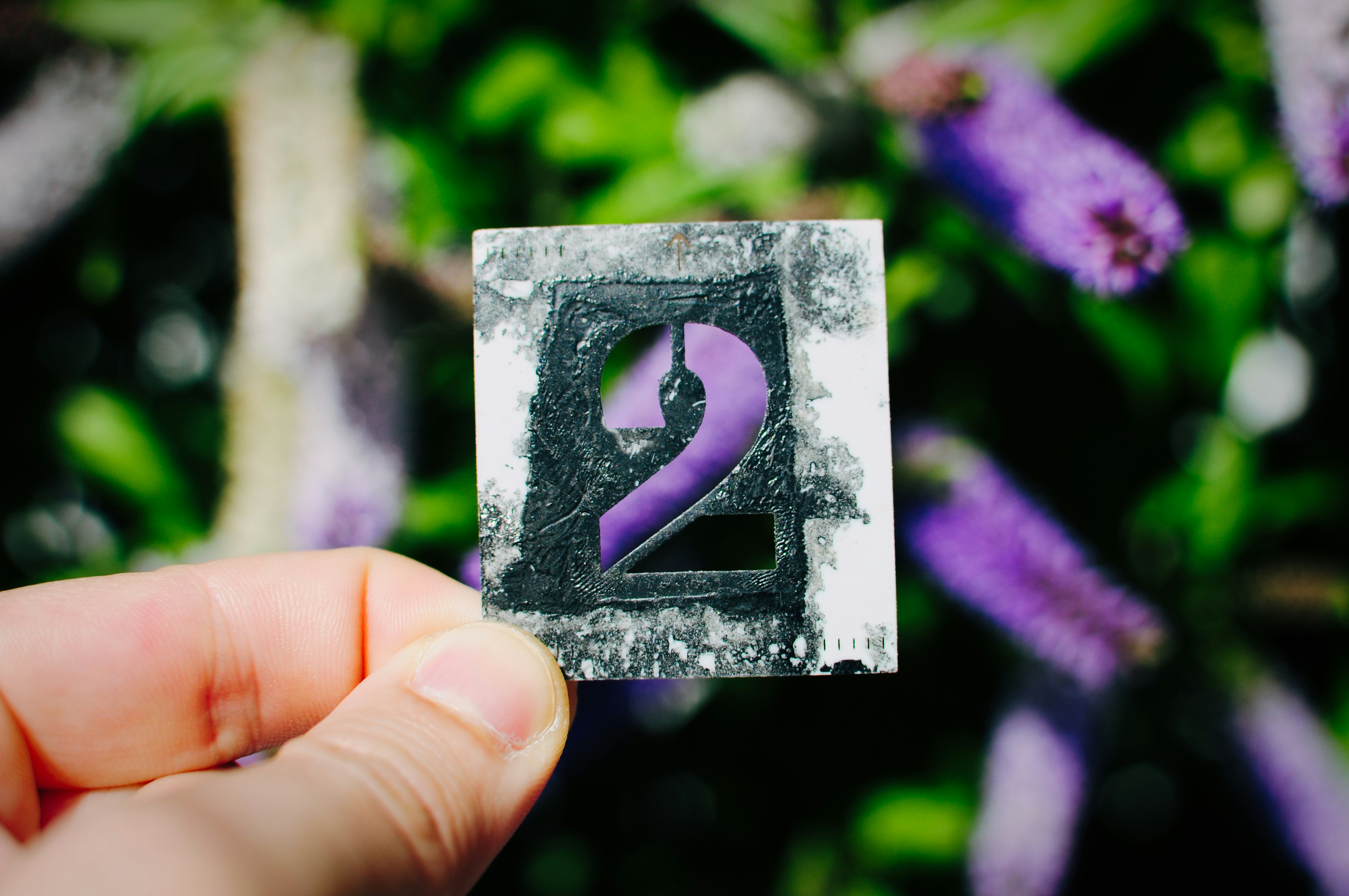 A hand holds a number two stencil