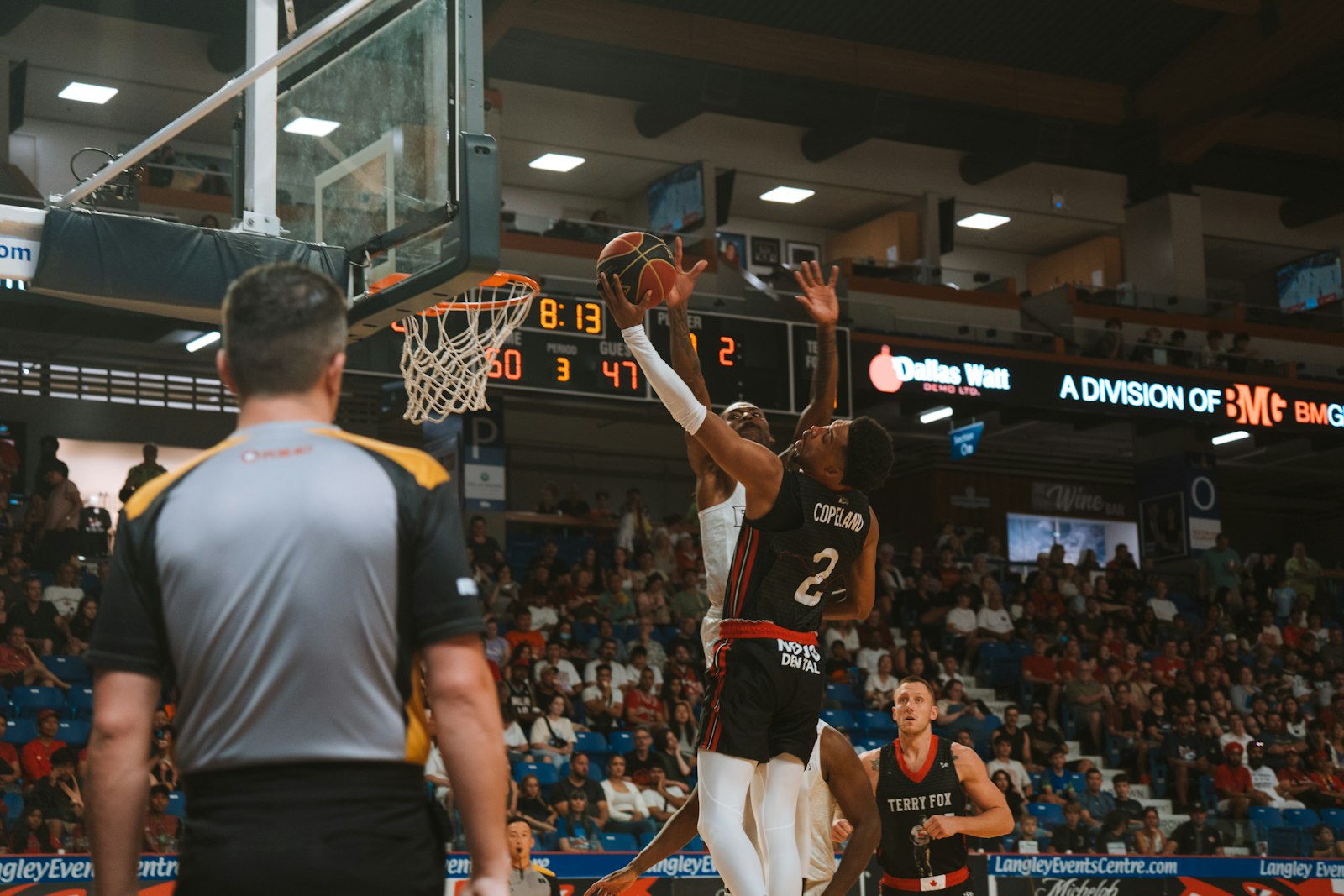 A basketball player rising for a shot under court lights — the kind of late-game explosive moment where calf and hamstring cramps decide possessions.