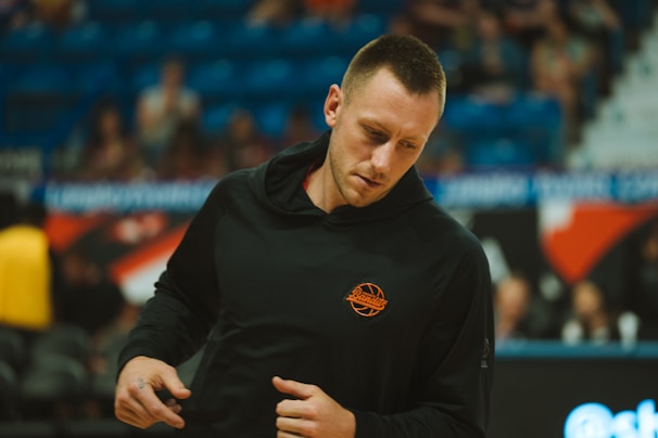 A basketball player wears a black hoodie.