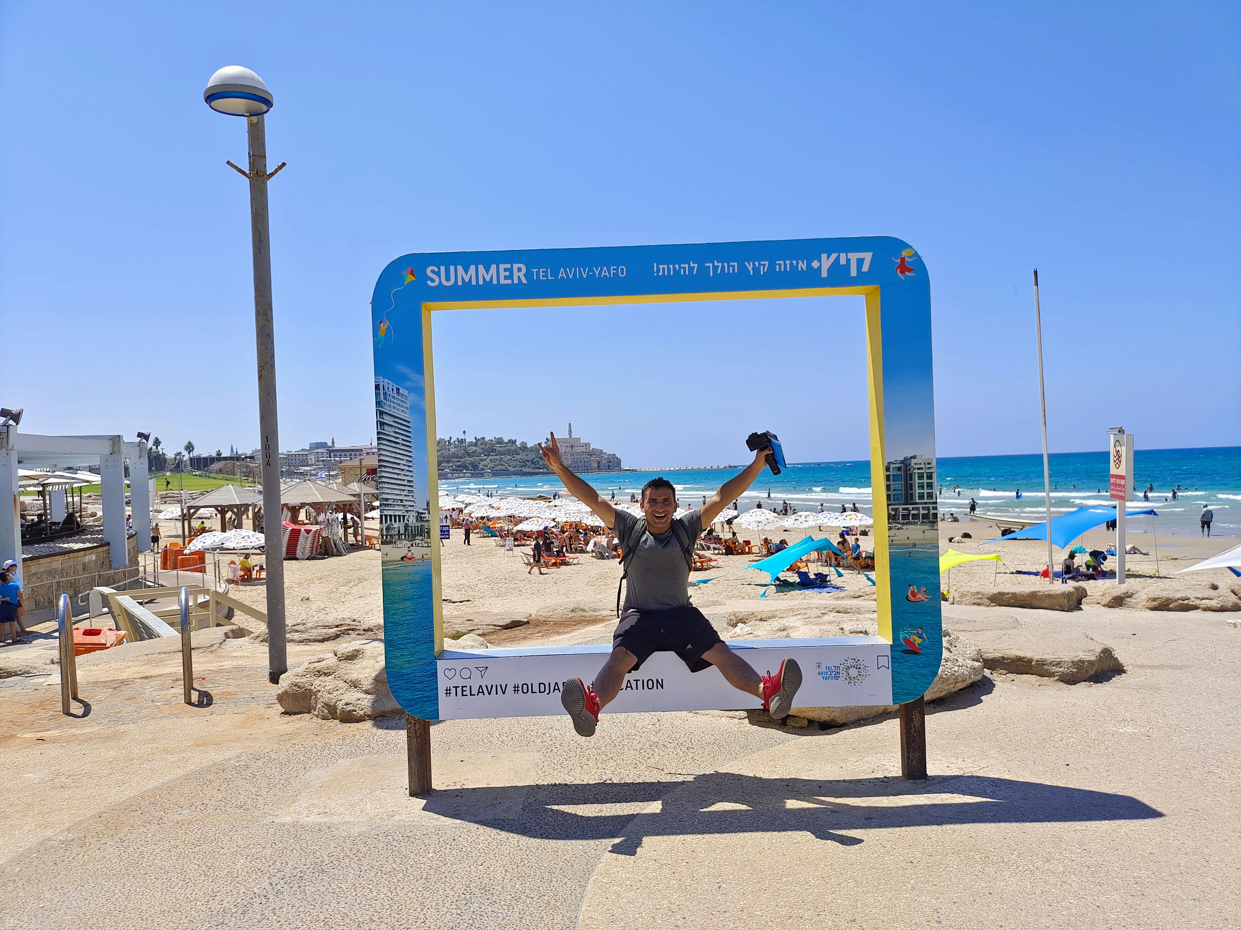 Man happily jumps through a frame at the beach.