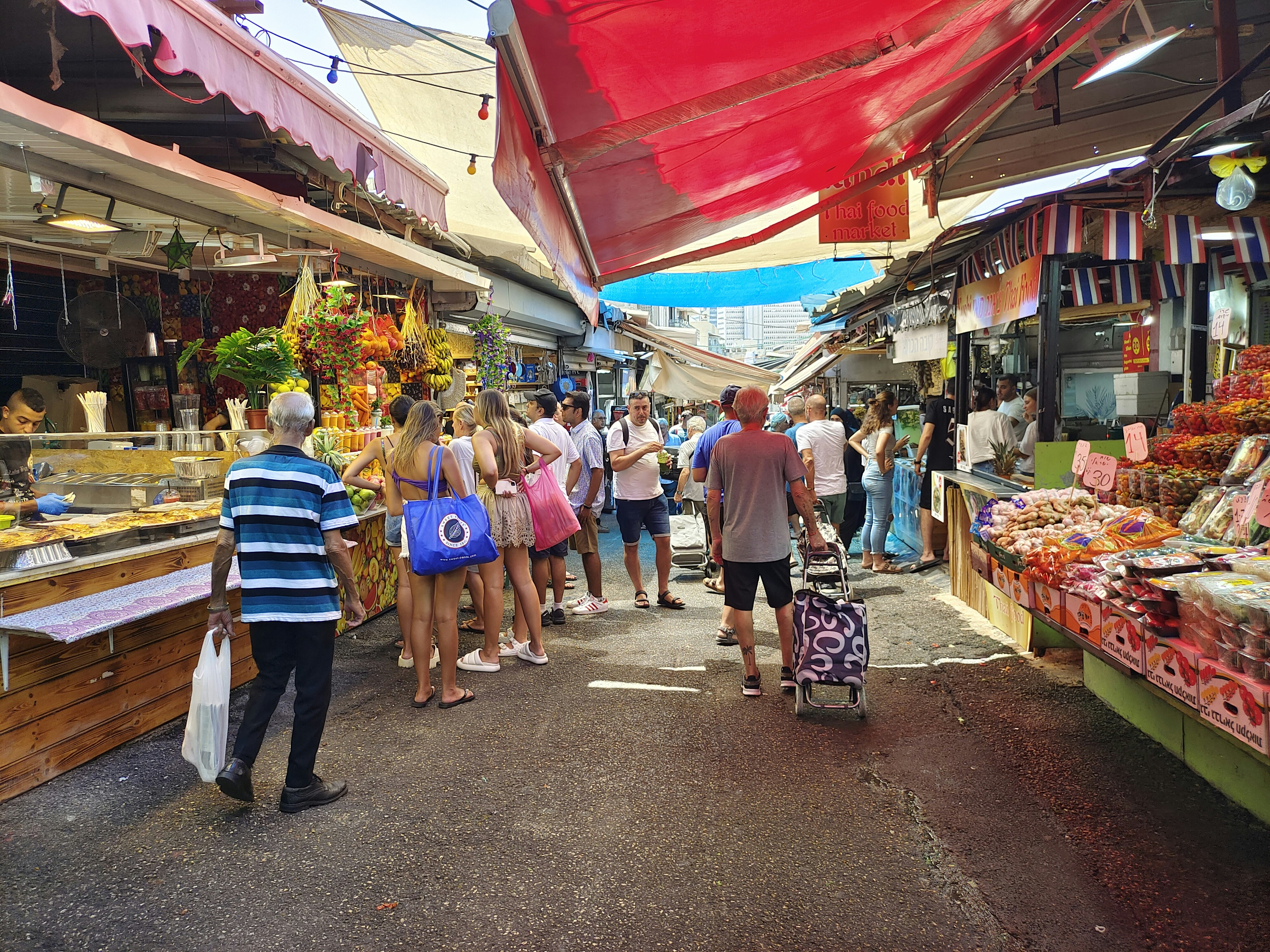 People shop and walk through a busy market.