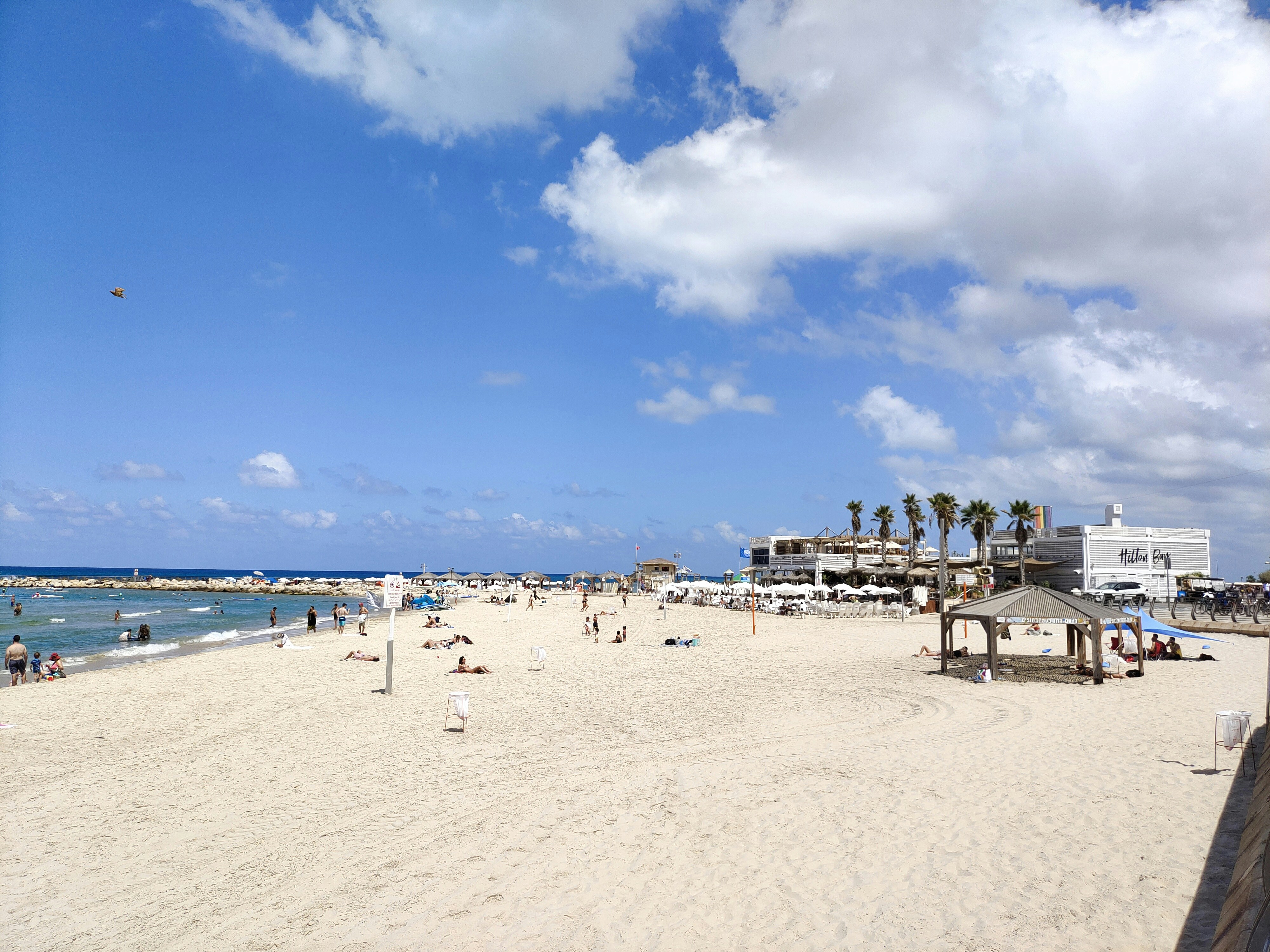 Beach day with blue sky and fluffy clouds.