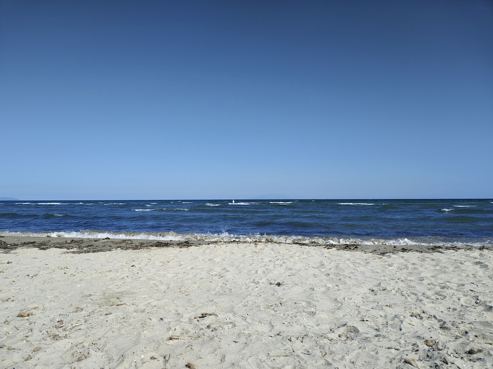 Beach with ocean under a bright blue sky.