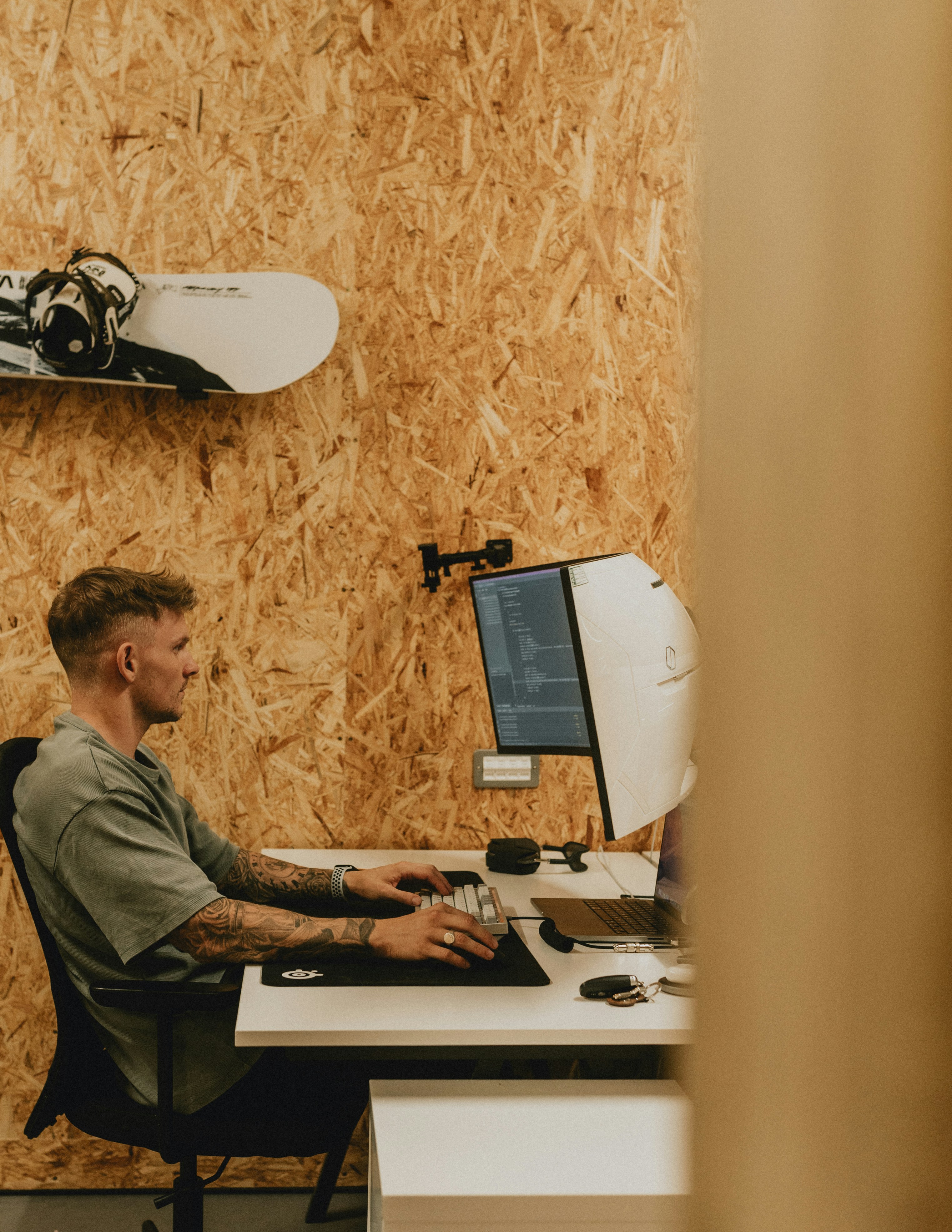 A man works at his computer in a wood-paneled room.