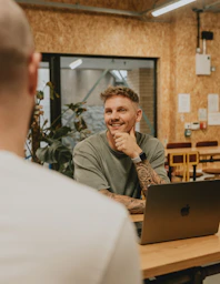A man smiles while talking to someone.