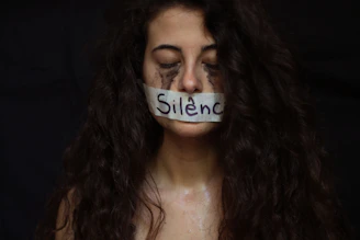 Silence symbolized by tape on a woman's mouth.