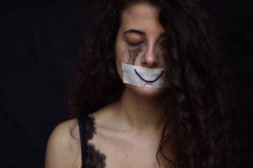 A sad woman with a smile tape over mouth.