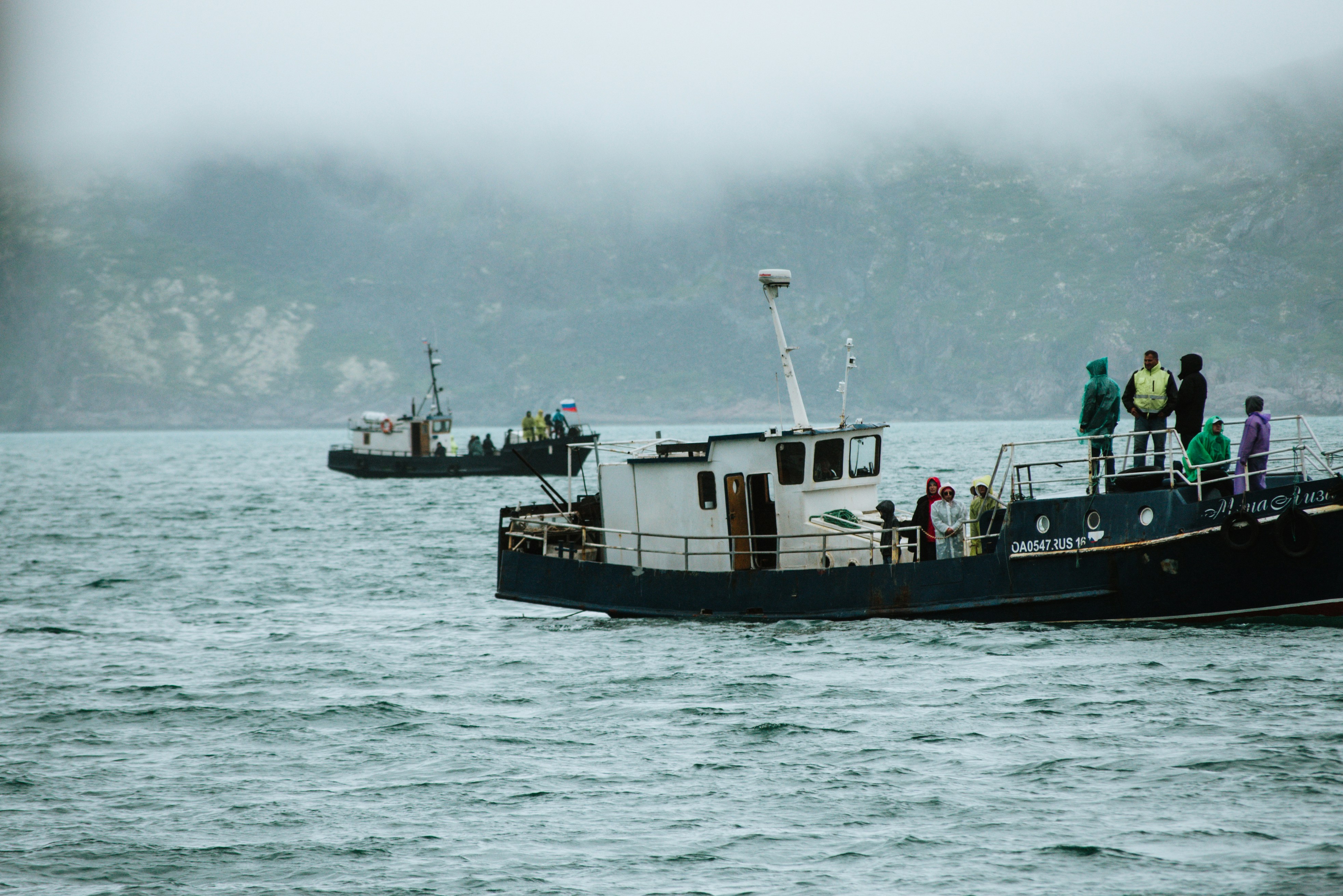 Boats sail on the water with a foggy background.