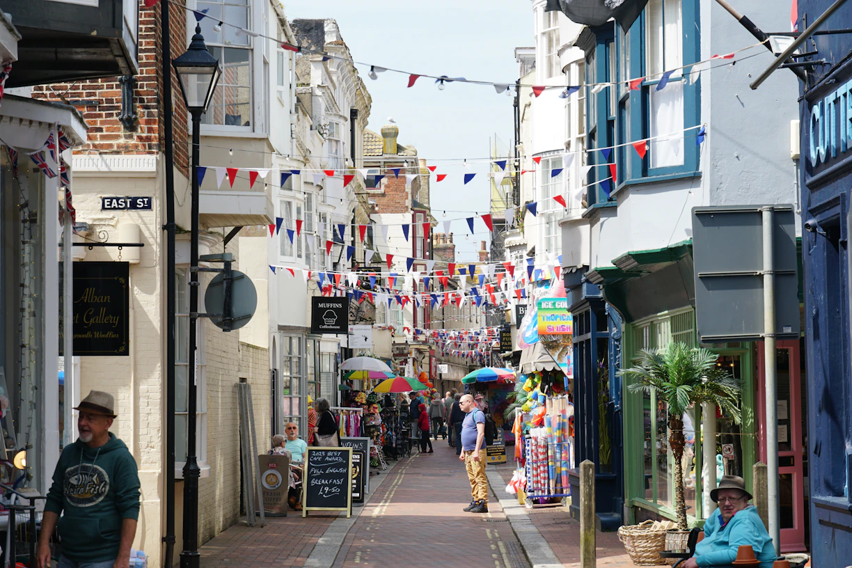 A narrow street is lined with shops and flags.