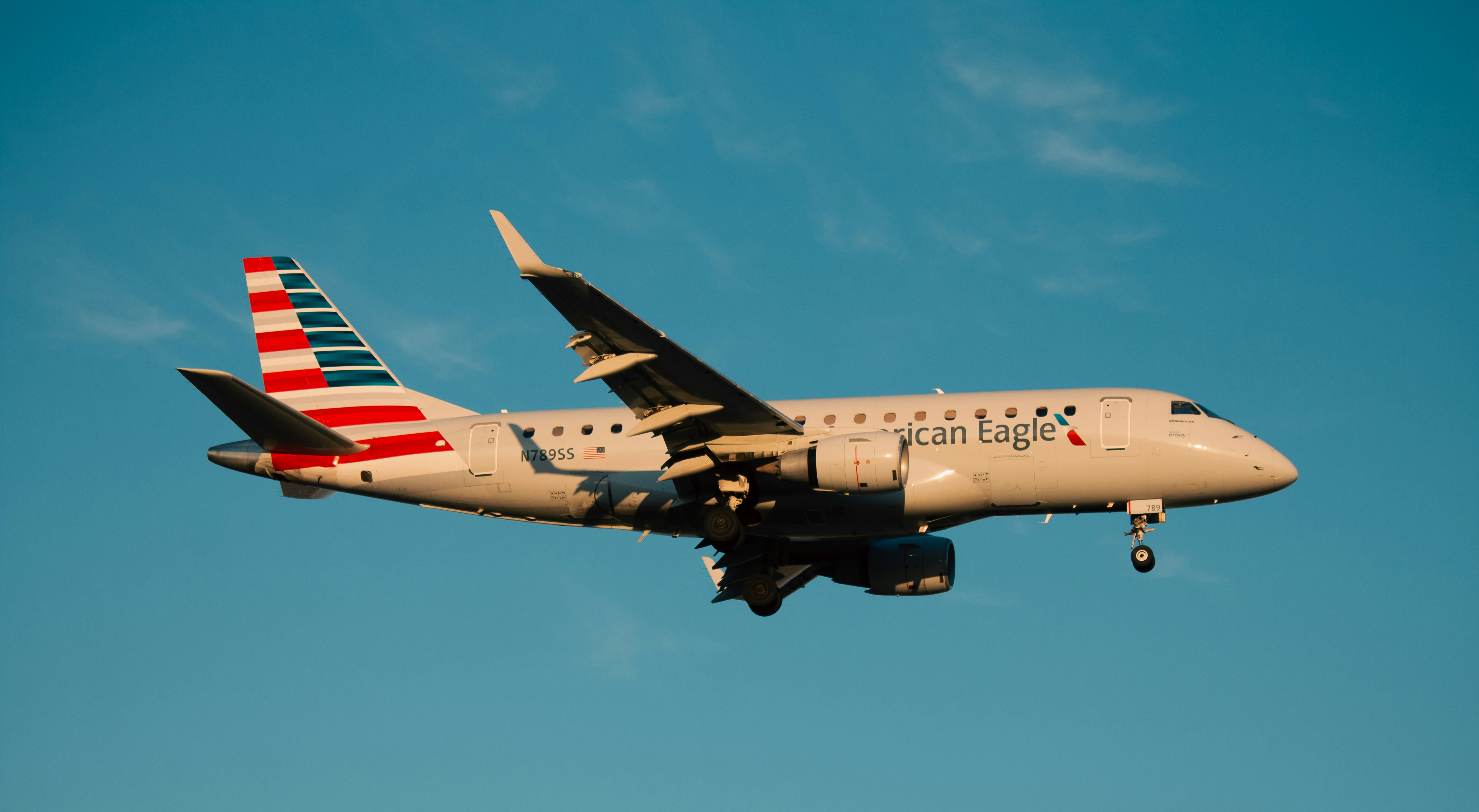 An american eagle plane is flying across a blue sky.