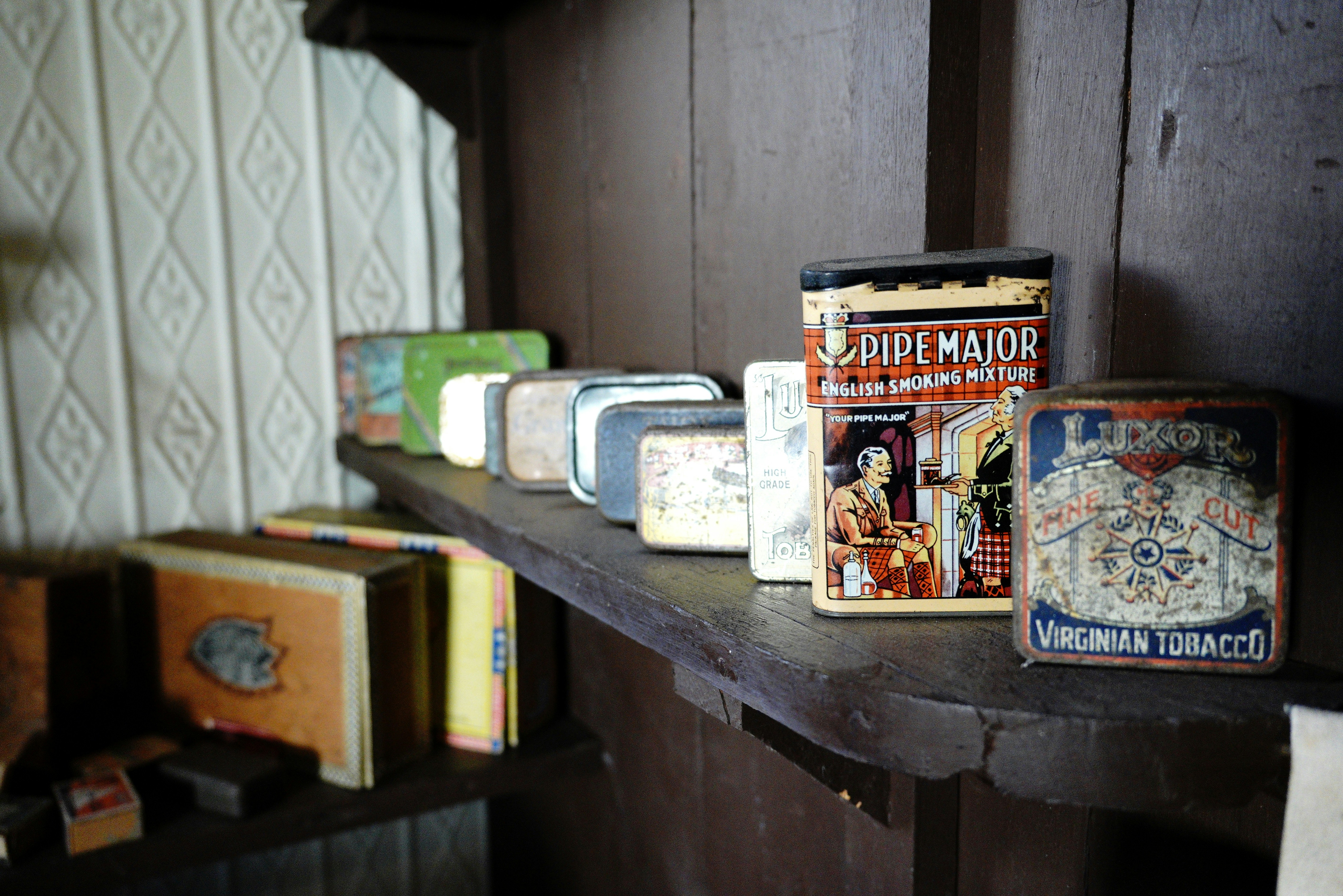 Vintage tobacco tins are displayed on a shelf.