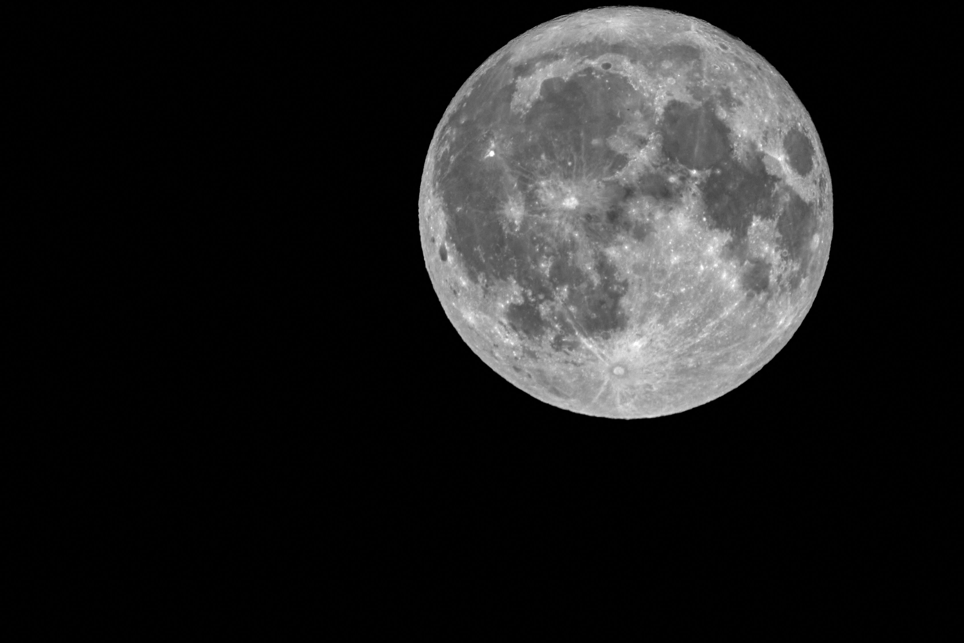 The moon shines brightly in the black sky.