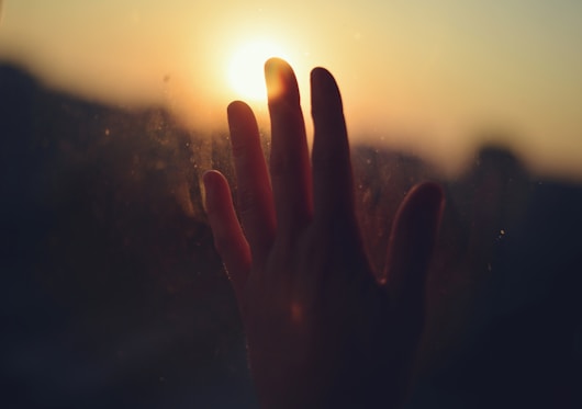 Hand reaching for the sunset, full of hope.