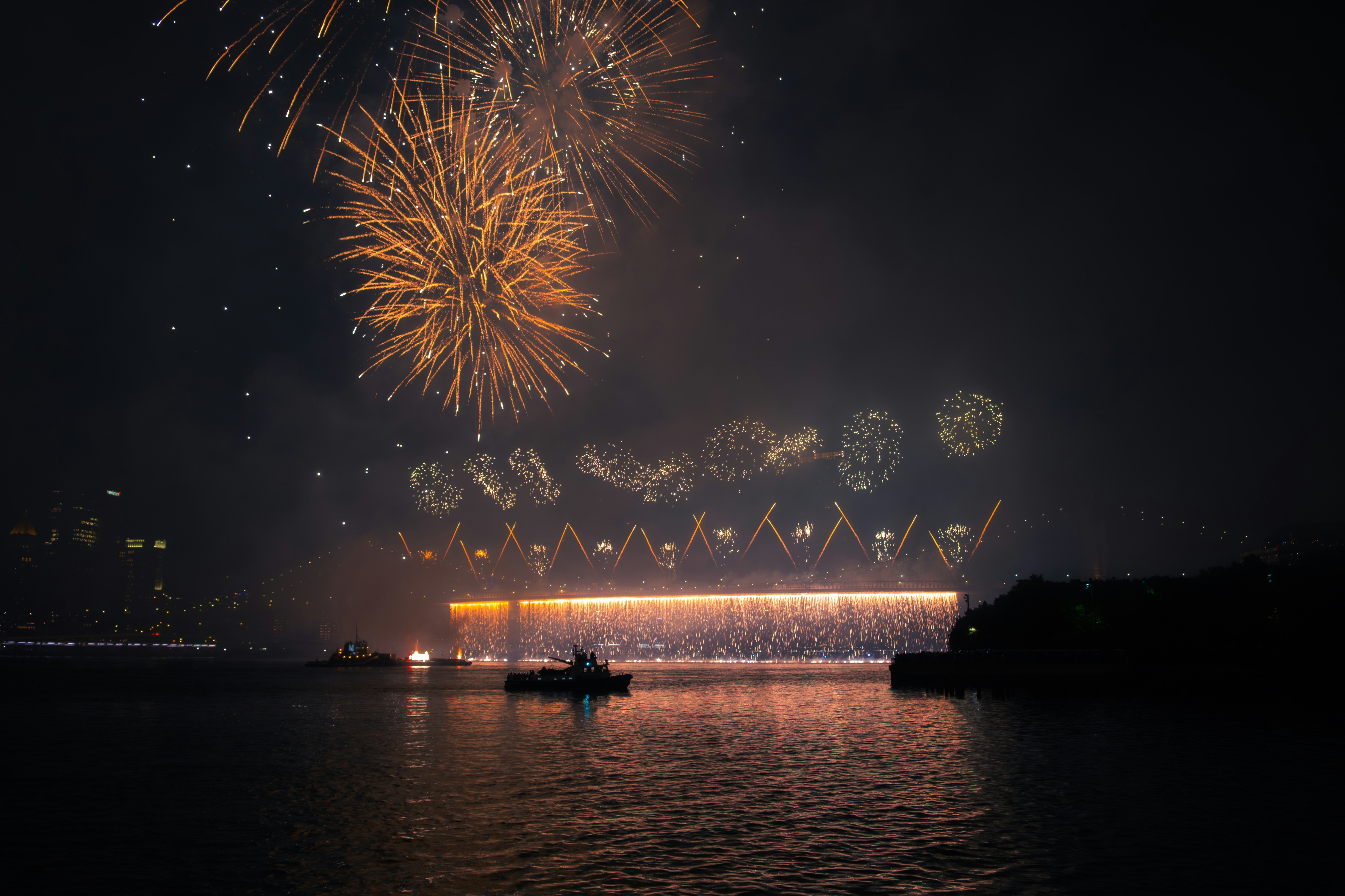 Fireworks light up the night sky over water.