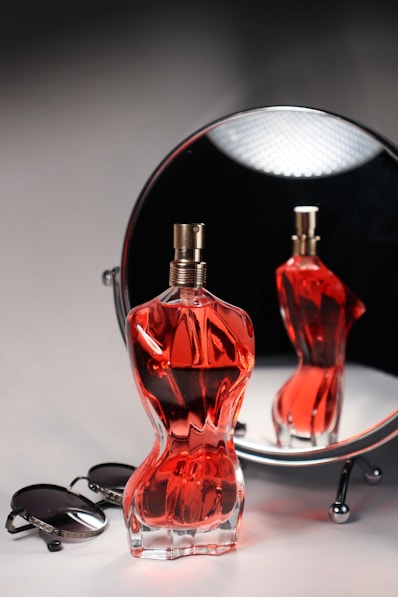 A perfume bottle is reflected in a mirror.