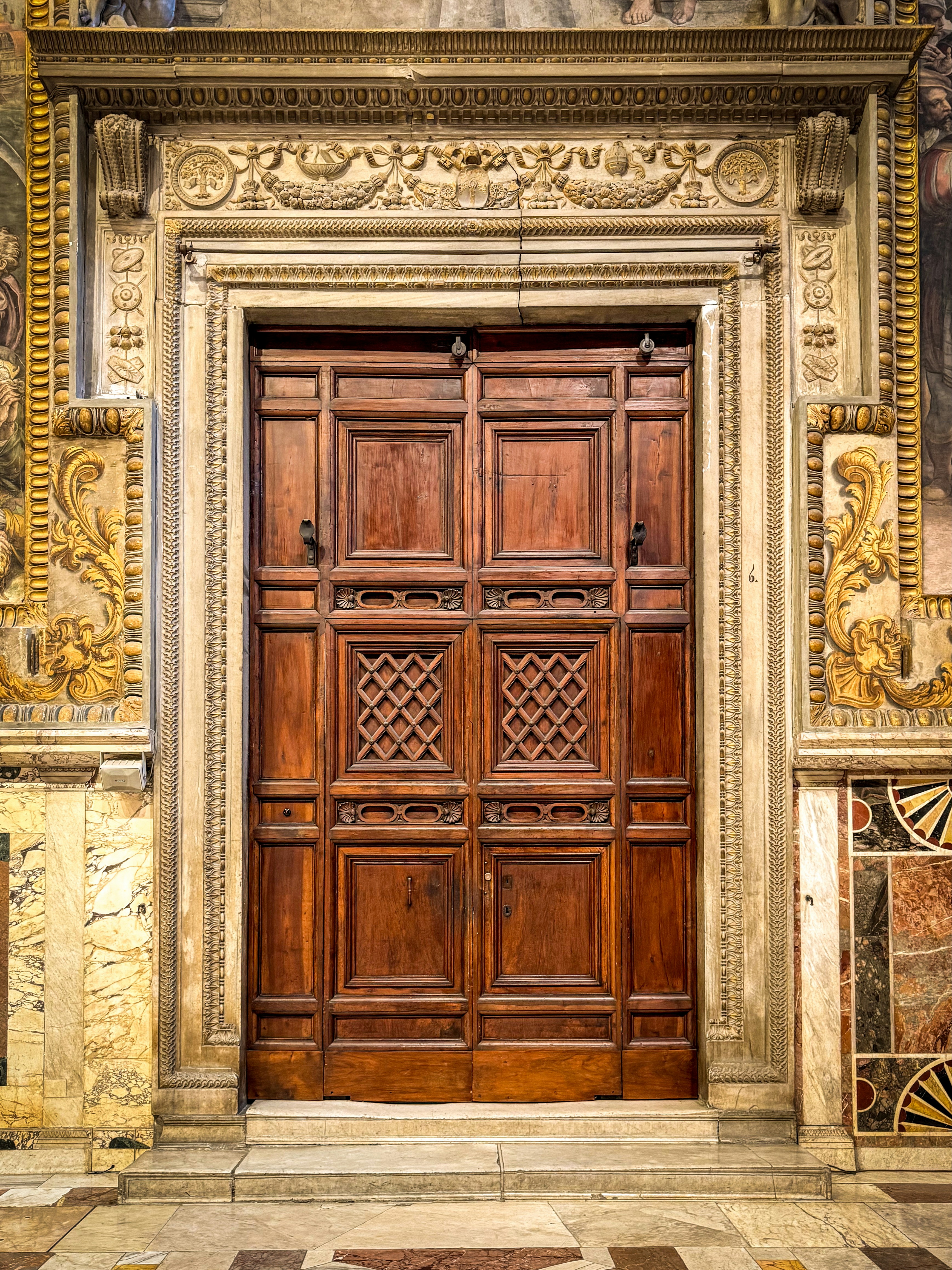 Porta in legno decorata all'interno di una cornice in pietra dettagliata.