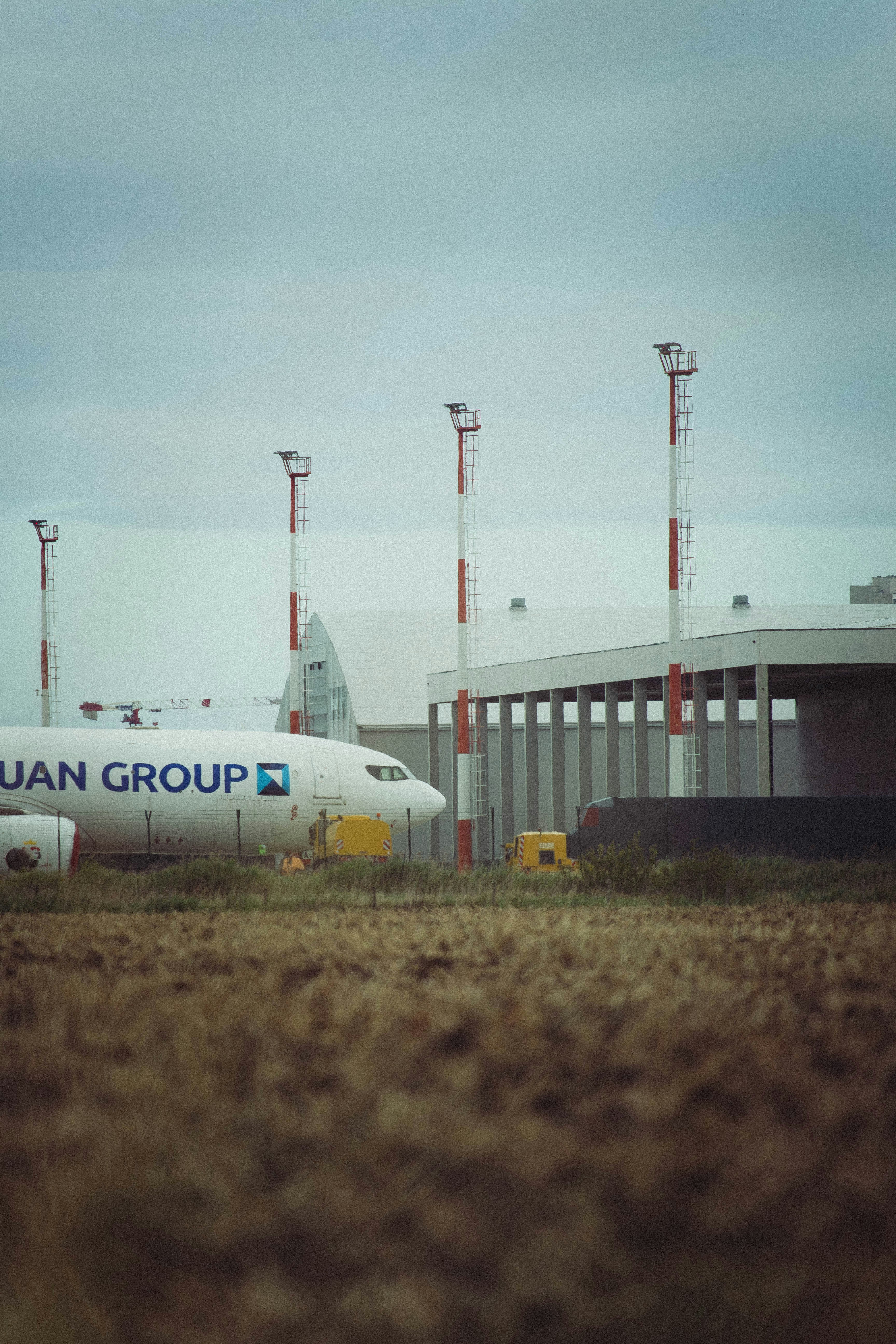 A plane sits at the airport under a cloudy sky.