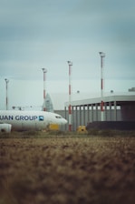 A plane sits at the airport under a cloudy sky.