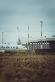 A plane sits at the airport under a cloudy sky.