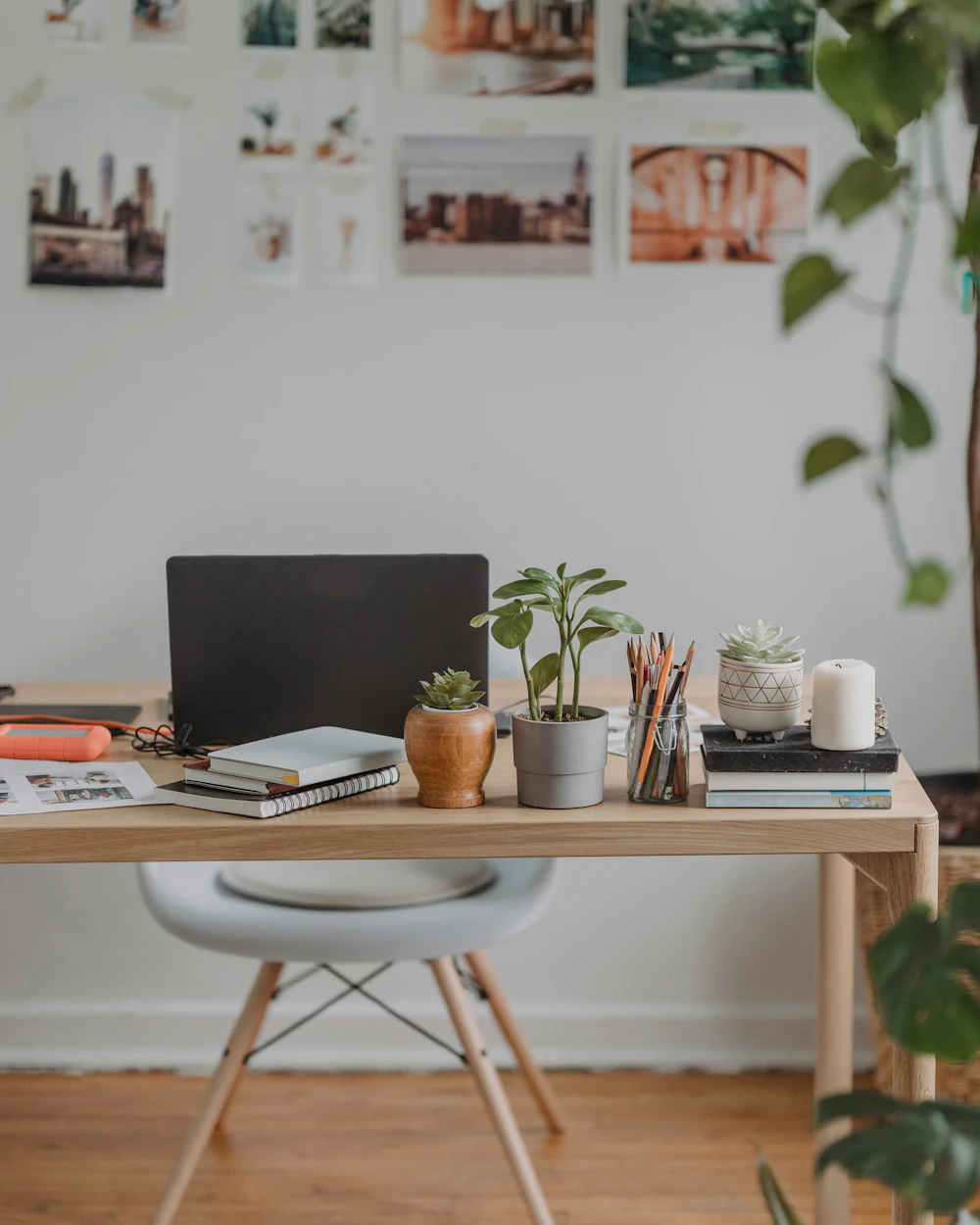 A quiet desk with a laptop, notebooks and plants