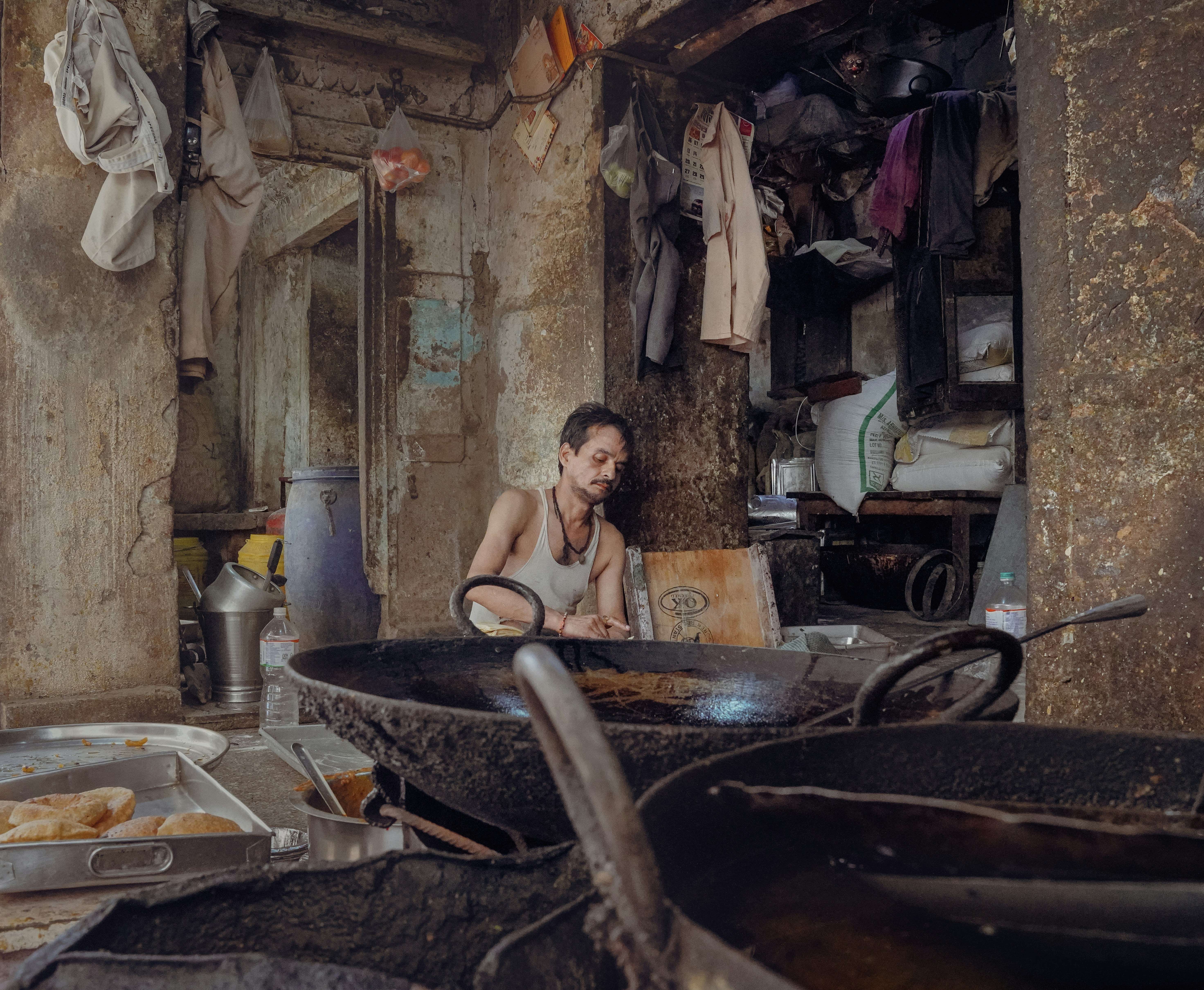 A man stands near large frying pans.