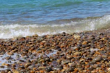 Waves gently wash over a pebble beach.