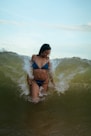 A woman in a bikini gets hit by a wave.