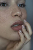 A woman with freckles and her hand on her lips.