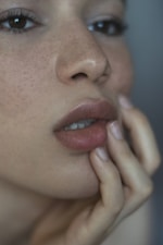A woman with freckles and her hand on her lips.