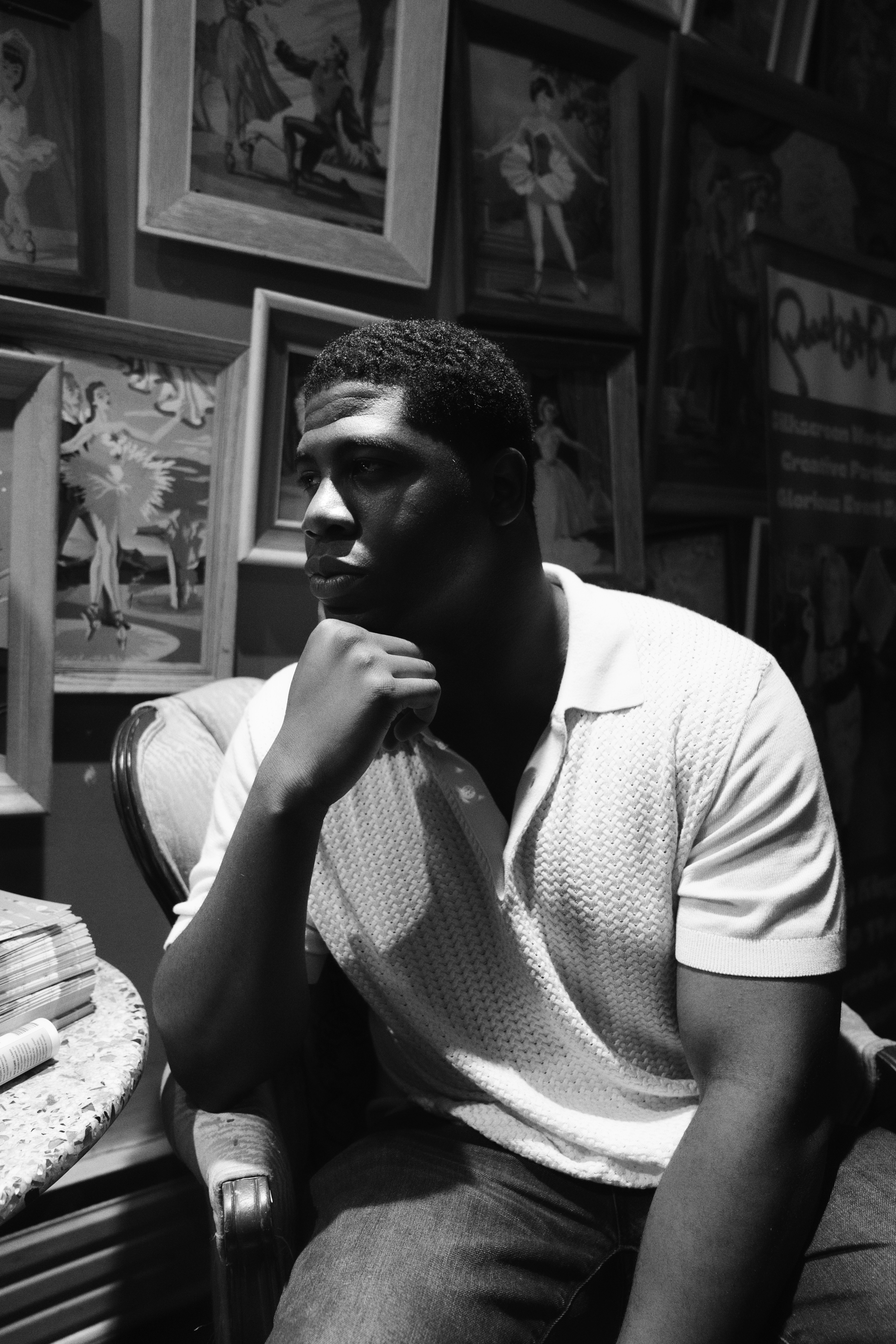 A man ponders amidst paintings.