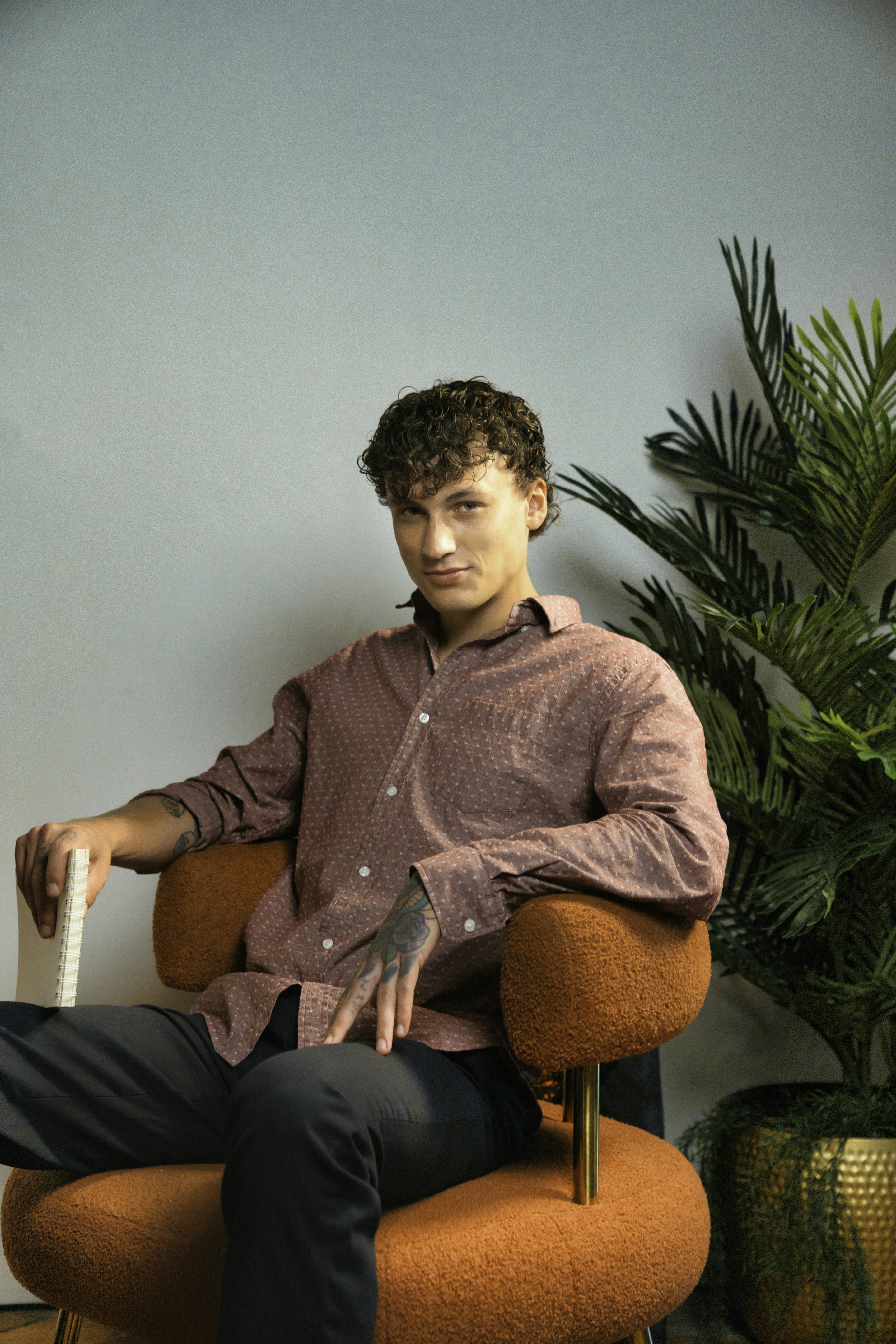 A man sits confidently in an orange chair.