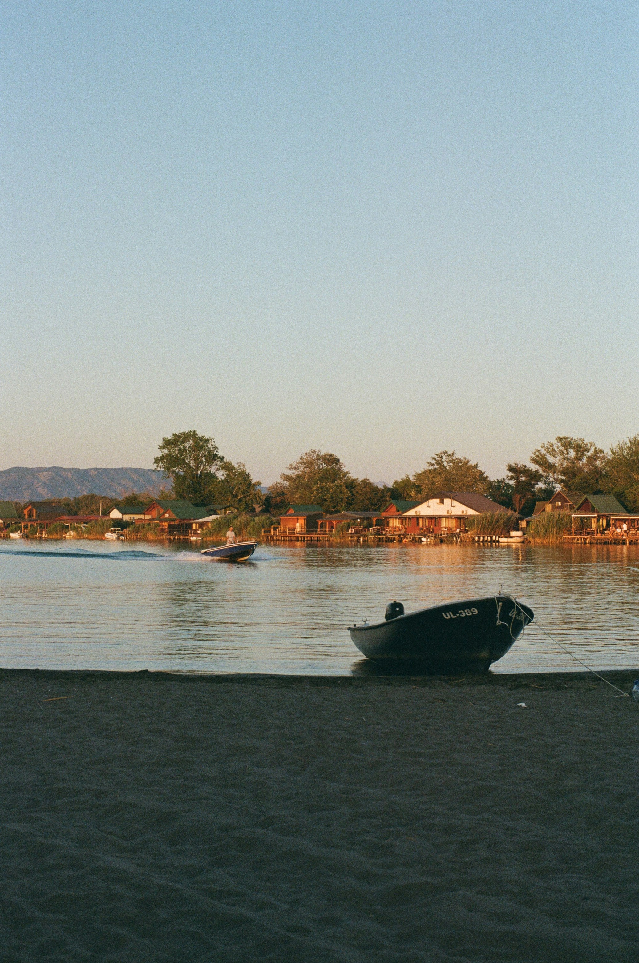 Boats on a lake near a quaint waterfront town.