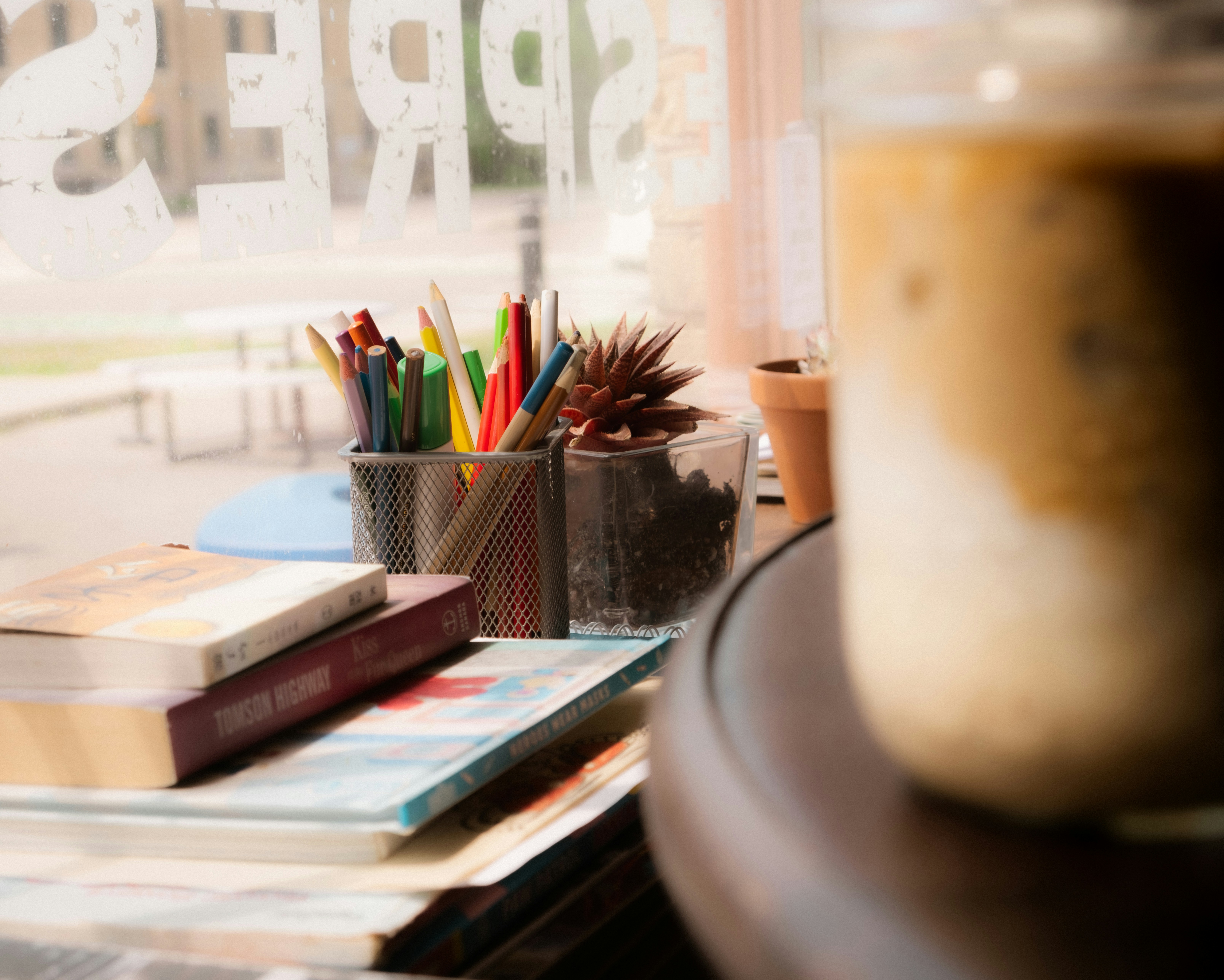 Coffee, books, and pencils sit on a window ledge.