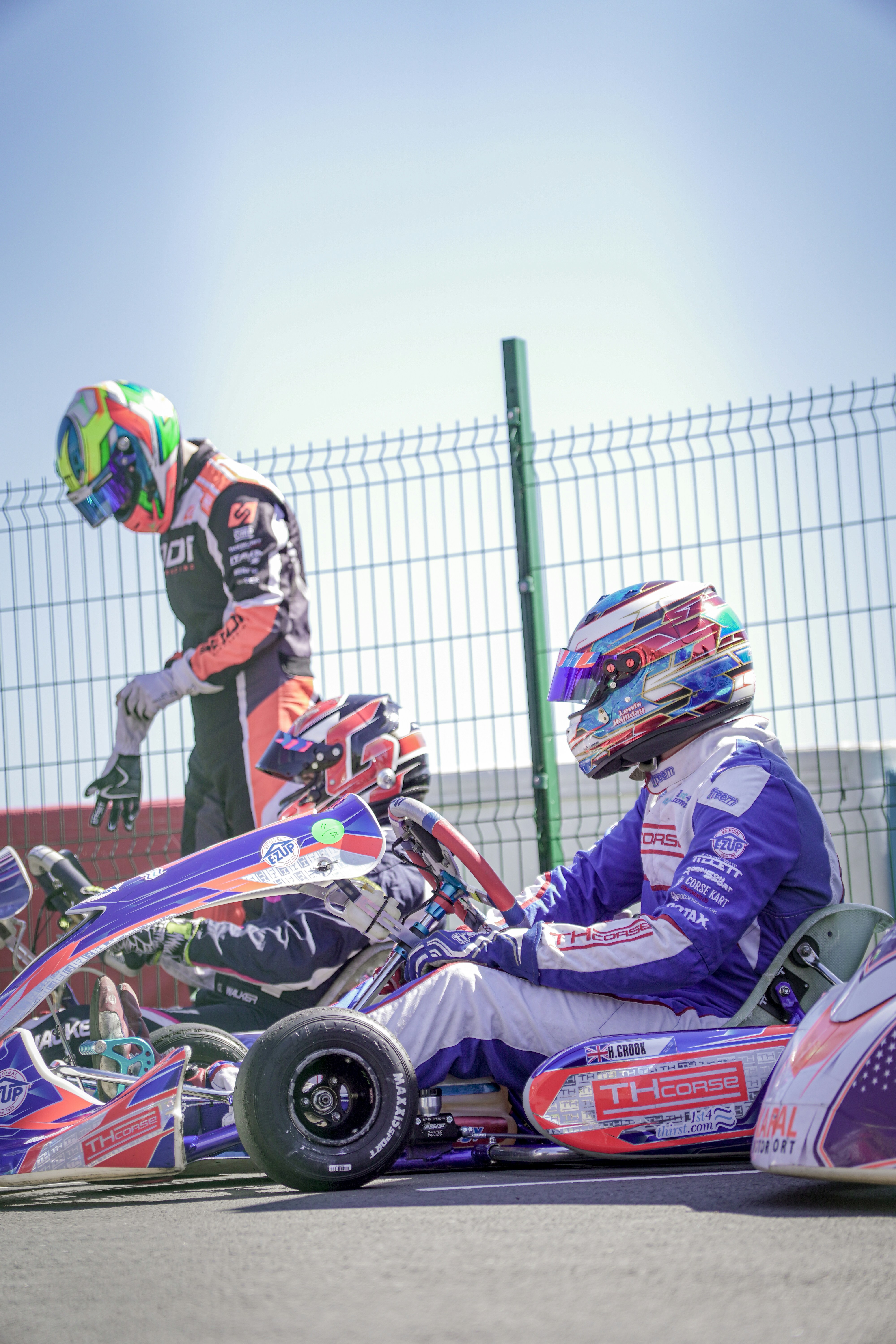 Two go-kart racers in colorful suits and helmets